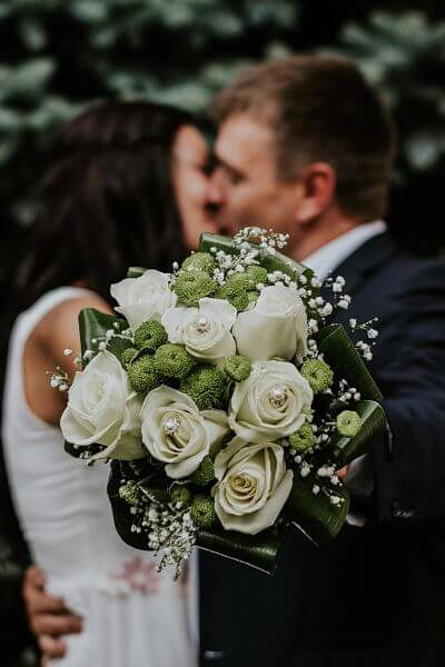 image of couple kissing with flower bouquet in their hands